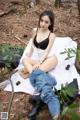 A woman sitting on a blanket in the woods.