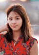 A woman in a red floral shirt posing for a magazine.