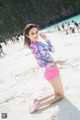 A woman in a pink bikini sitting on a beach.