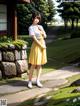 A woman in a yellow dress standing in front of a house.