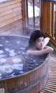 A woman laying in a wooden tub filled with water.