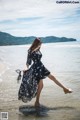 A woman in a black dress is standing in the water.