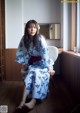 A woman in a blue and white kimono sitting on a chair.