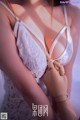 A woman in a white lingerie holding a wooden mannequin.