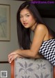 A woman in a black and white checkered dress sitting on a chair.