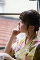 A woman in a kimono sitting by a window.