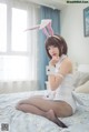 A woman in a bunny costume sitting on a bed.