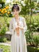 A woman in a white robe standing in a garden.