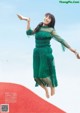 A woman in a green dress jumping in the air.